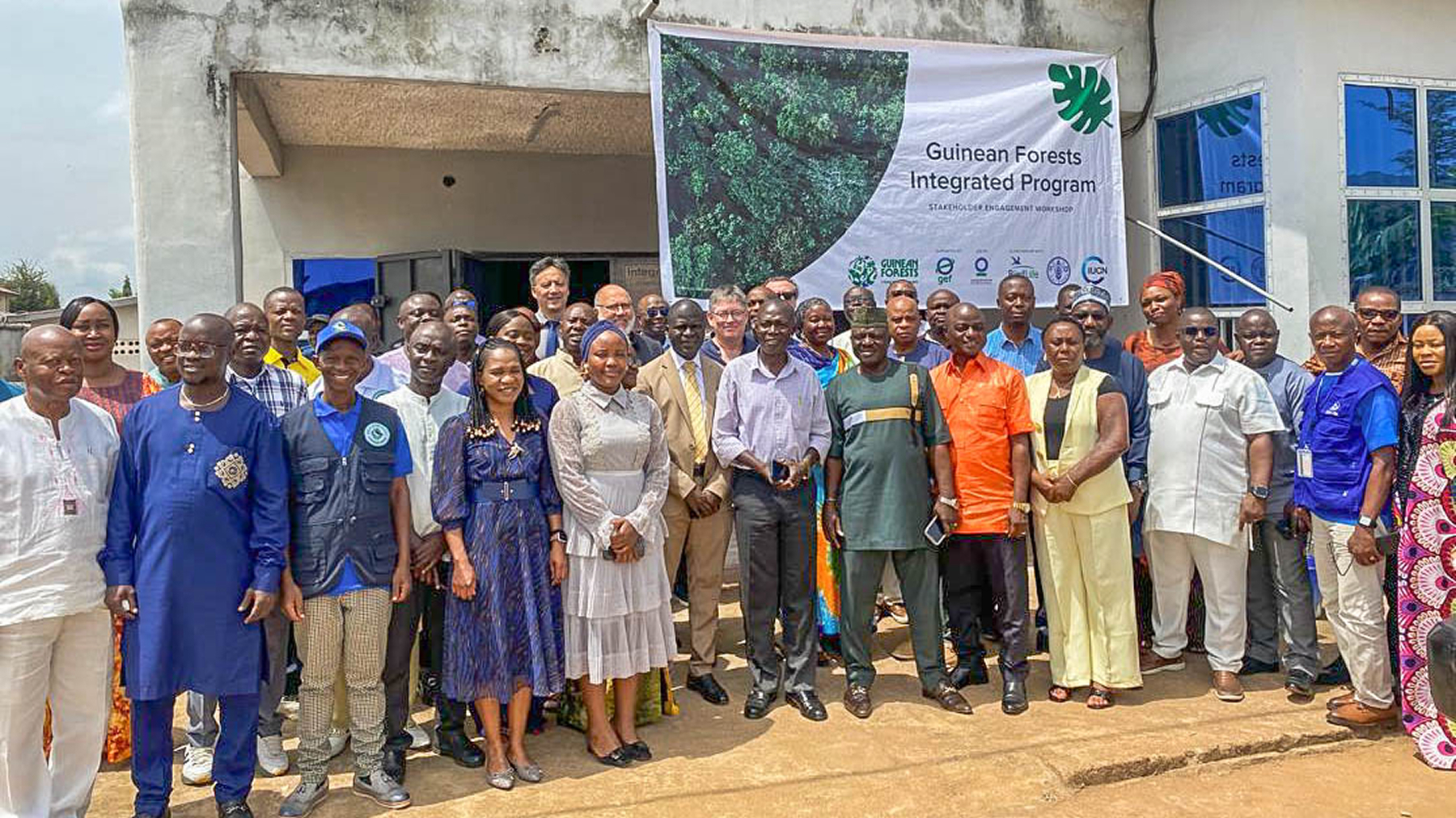 A group of stakeholders posing in front of a building with a banner for the GFIP.