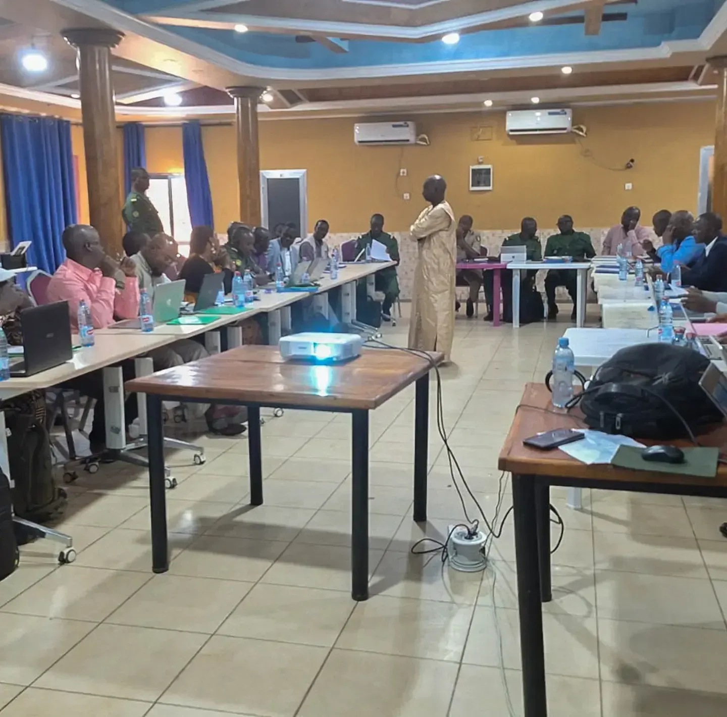 A group of professionals and officials attend a presentation in a conference hall.